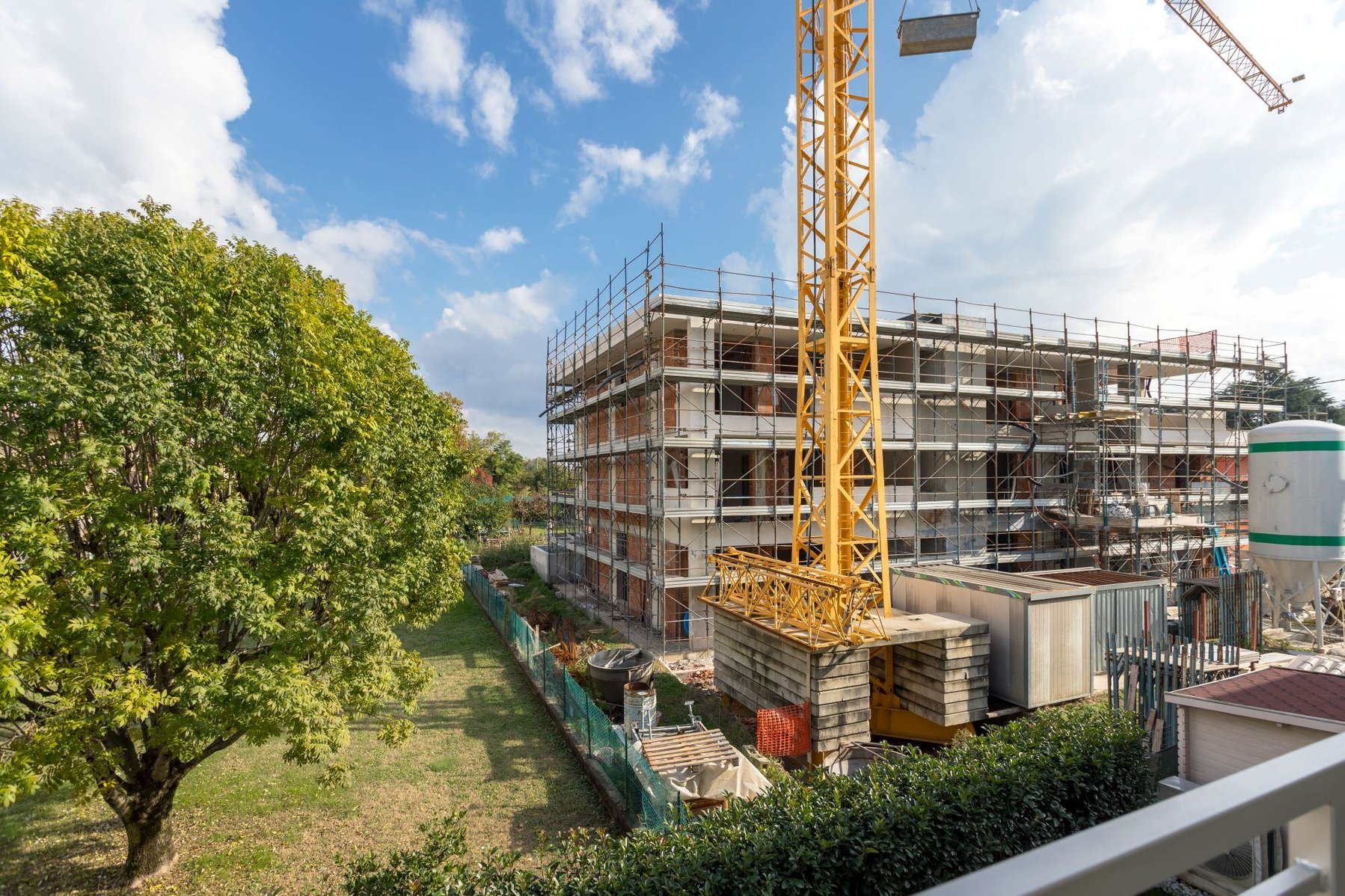 Construction site with crane and green trees